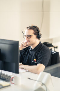 Mann mit Brille und Headset am Schreibtisch