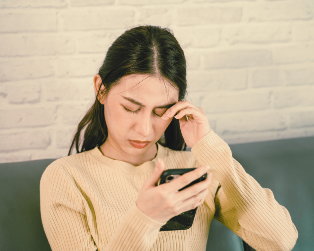 Frau, die sich vor dem Handy die Augen reibt